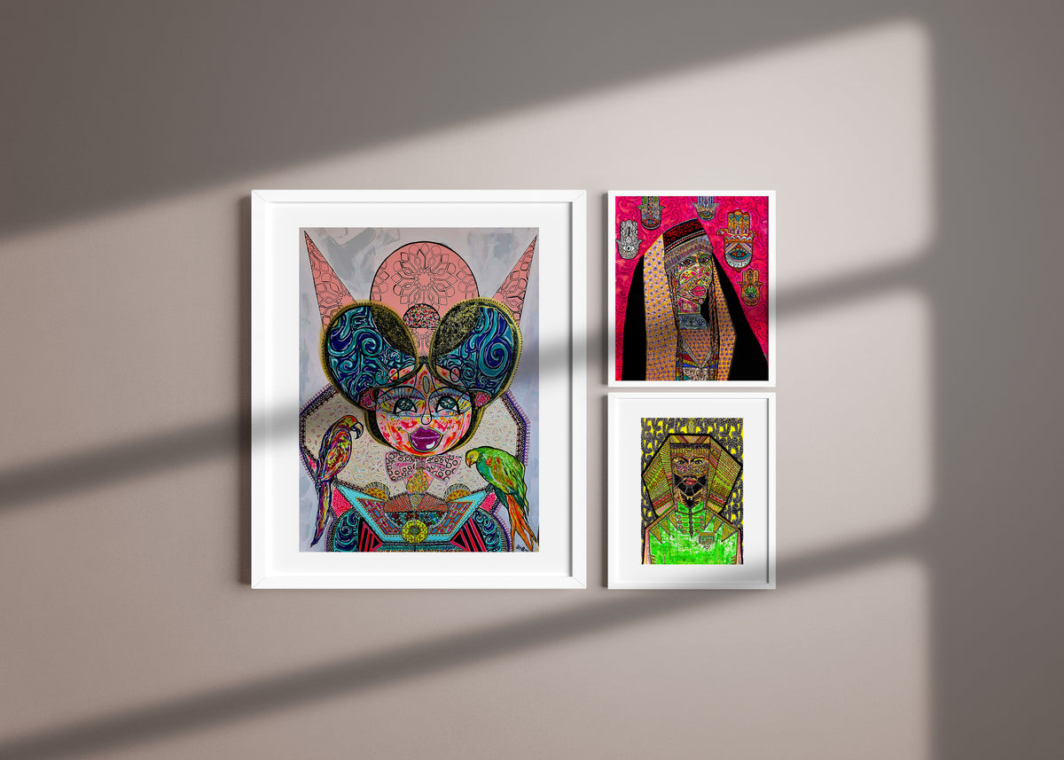 Three Shabsoug Art prints in white frames arranged on a wall in dappled sunlight