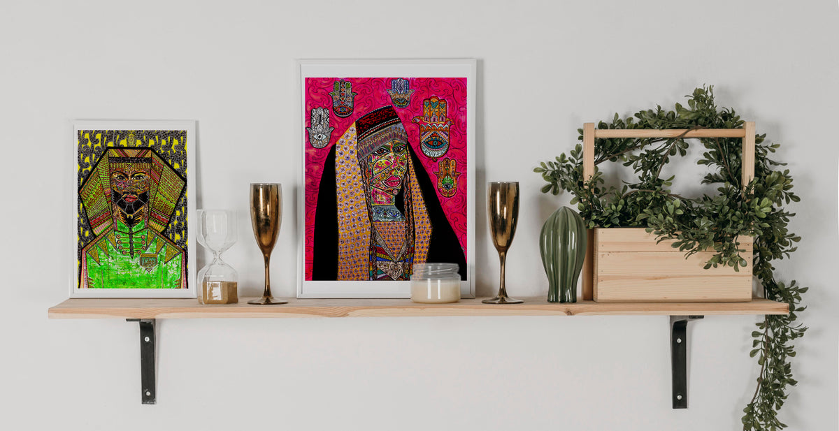 Shabsoug Art prints framed on a timber shelf with candles, an hourglass and trailing greenery