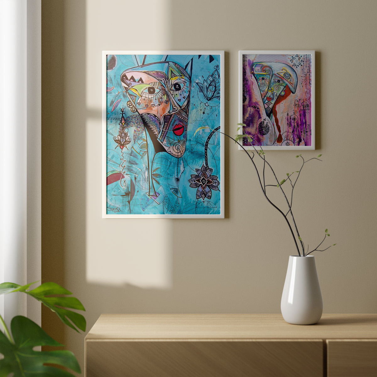 Two Shabsoug Art prints framed in white, hung side by side above a timber sideboard in soft daylight