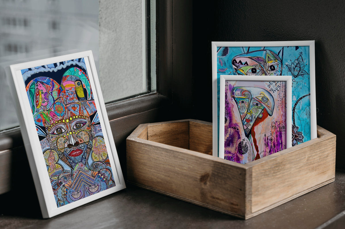 Shabsoug Art prints in white frames resting in a wooden crate beside a window