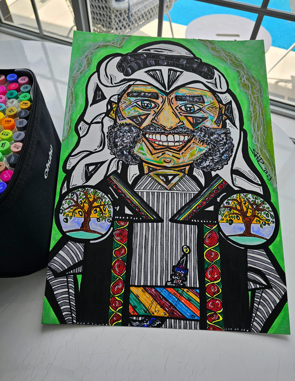 Khan Younis: the painting propped at an angle on a table beside a pot of marker pens