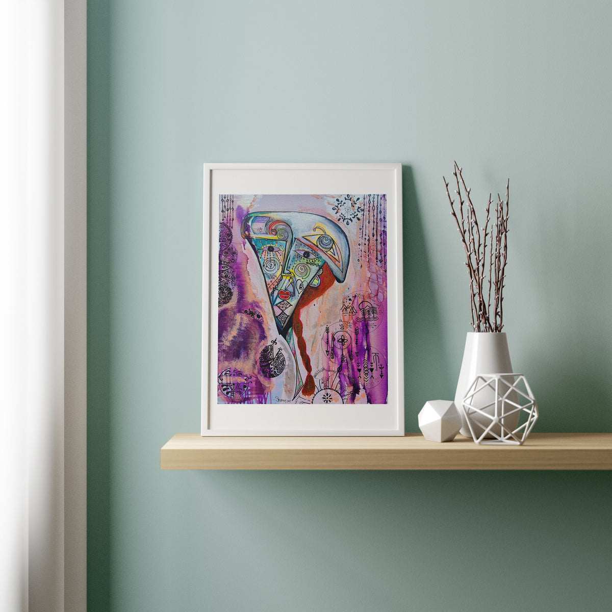 Rosado print framed in white on a timber shelf against a sage wall, beside a vase of twigs