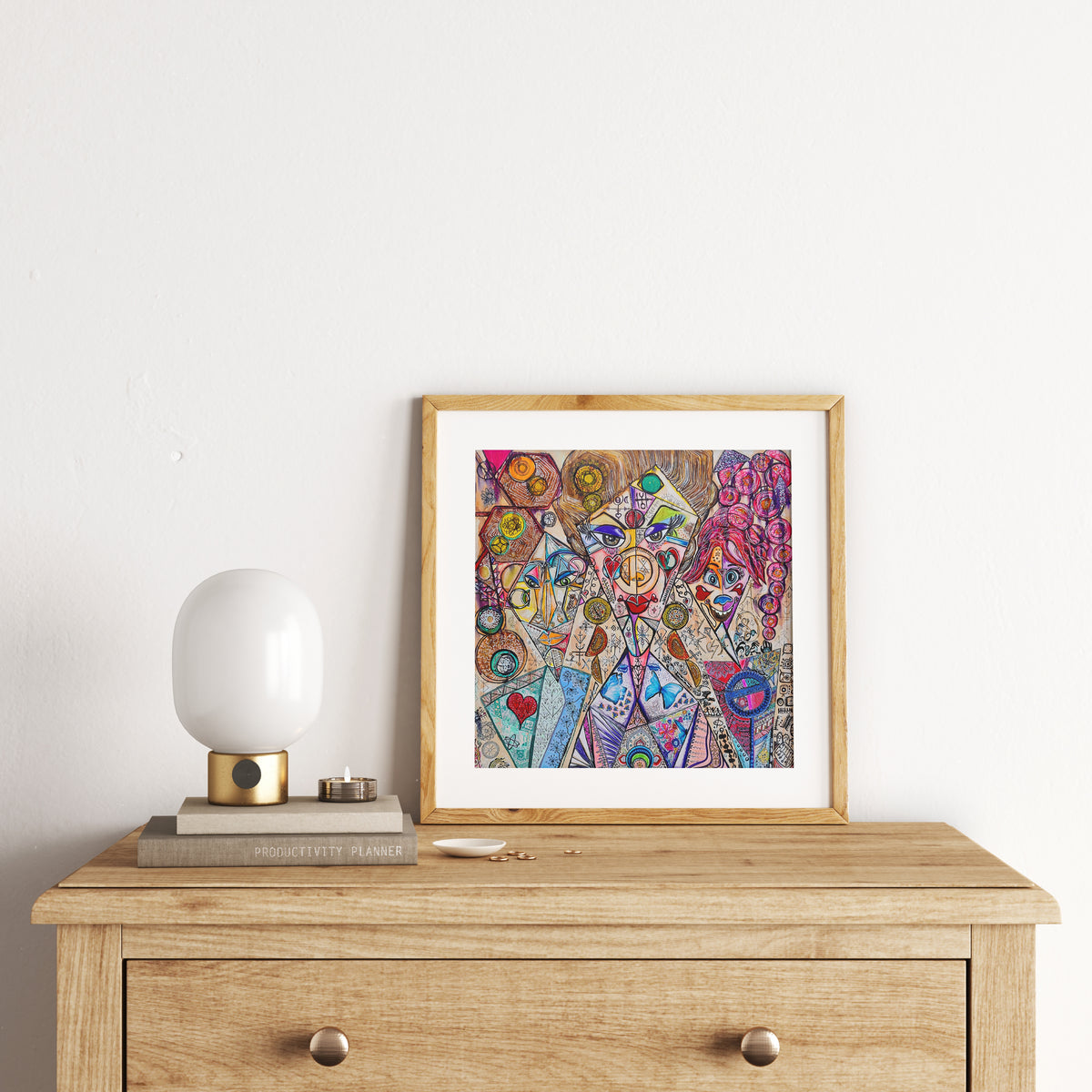 Trinity print framed in oak on a timber chest of drawers, beside a rounded white table lamp