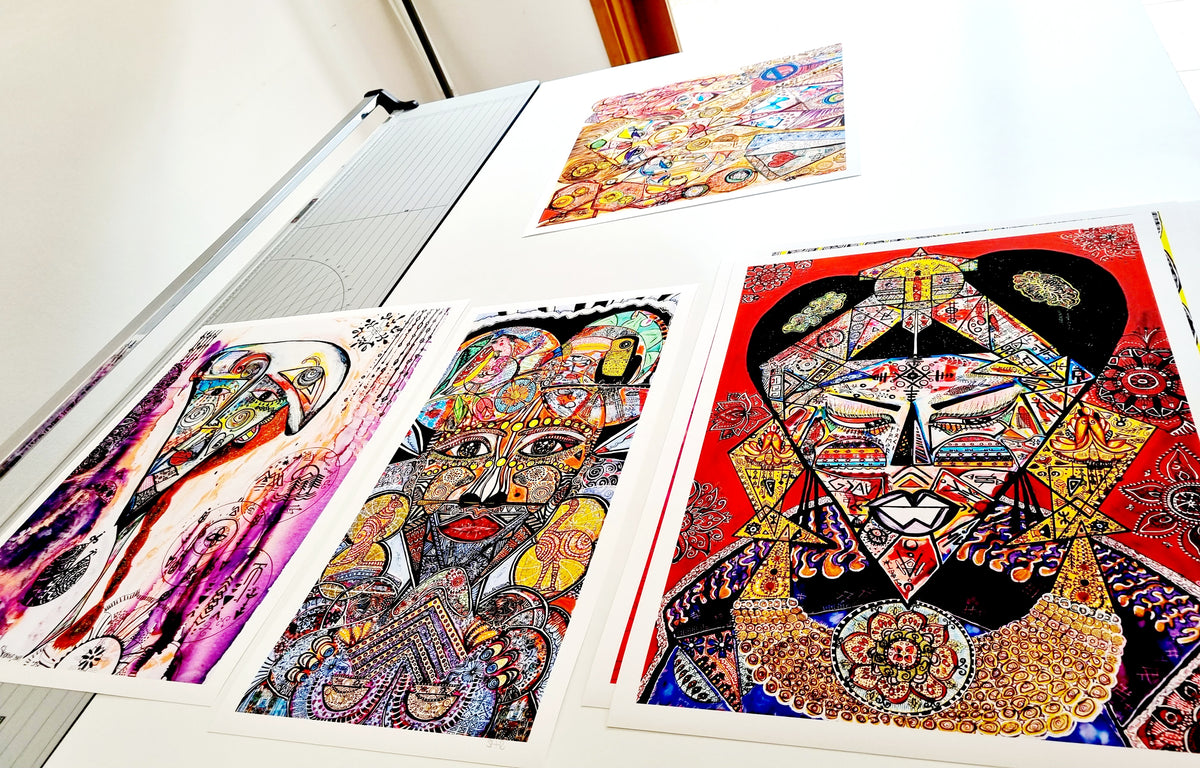 A group of Shabsoug Art fine art prints laid out on a studio table, showing the paper, white borders and colour
