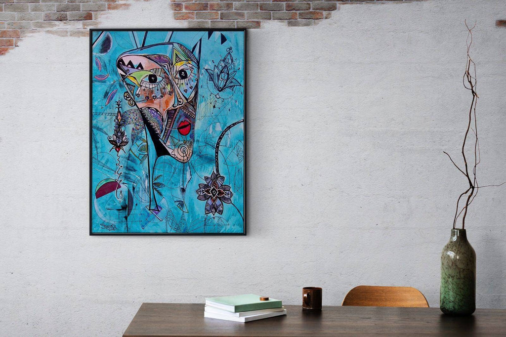 Azul print framed on a white brick wall above a wooden desk with books and a tall vase